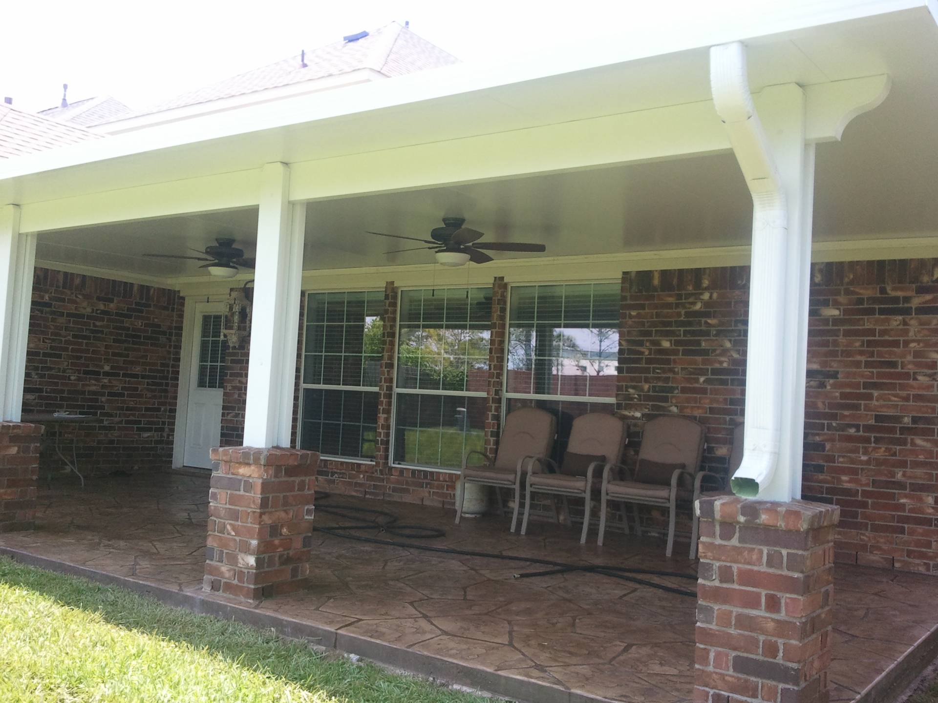 Outdoor Patio Deck Cover in Spring, TX with brick columns attached to a house.